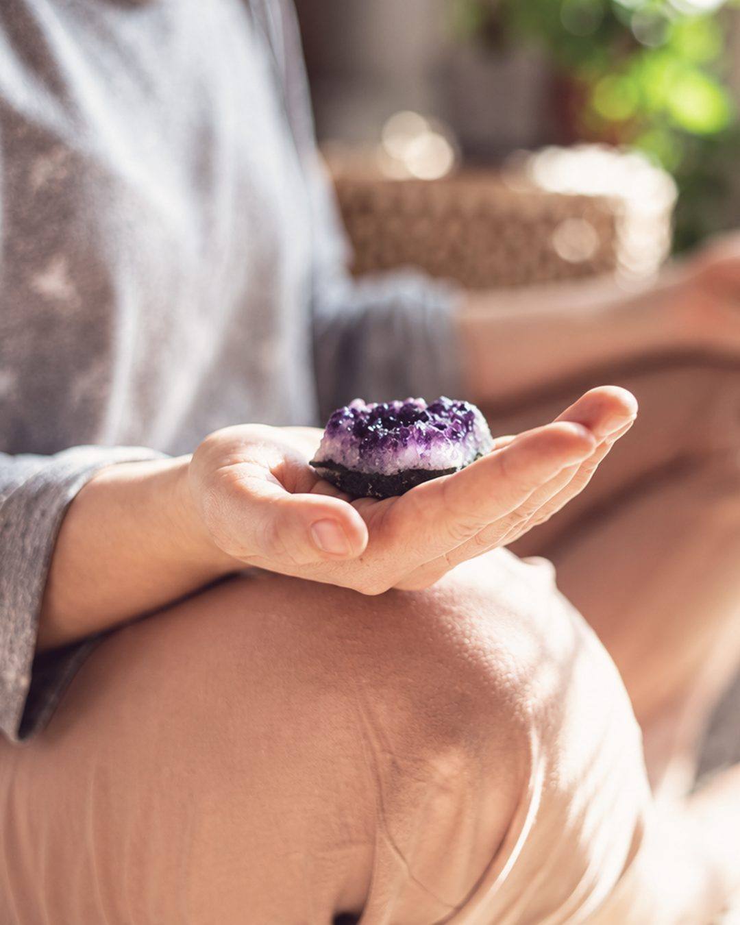 Open hands holding an amethyst geode during a quiet moment of rest