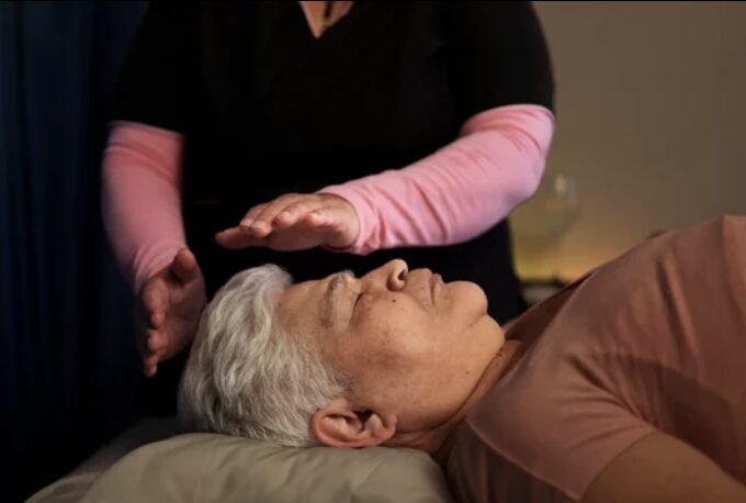 Reiki practitioner with hands above a resting patient