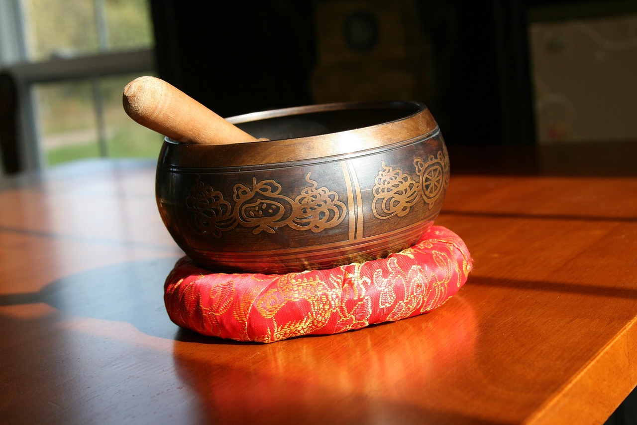 A Tibetan singing bowl resting on a cushion, played gently with a wooden mallet